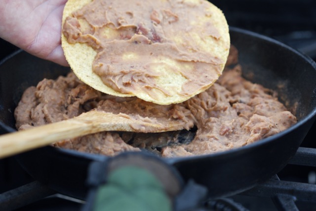 Placing re-fried beans on the tostada shell